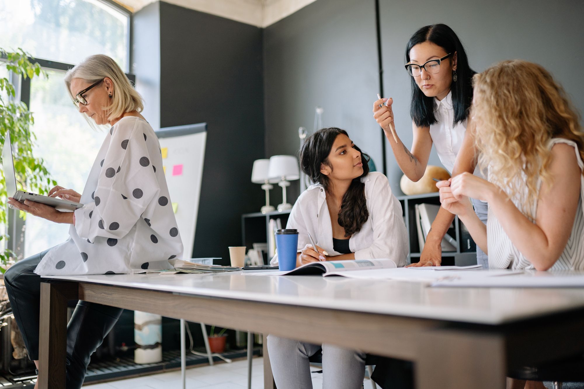 Grupo de mulheres conversando em torno de uma mesa de trabalho em um escritório