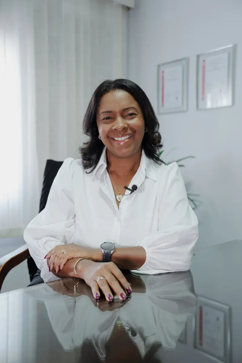 Profissional da Fortes Assessoria Contábil sorrindo, sentada à mesa do escritório